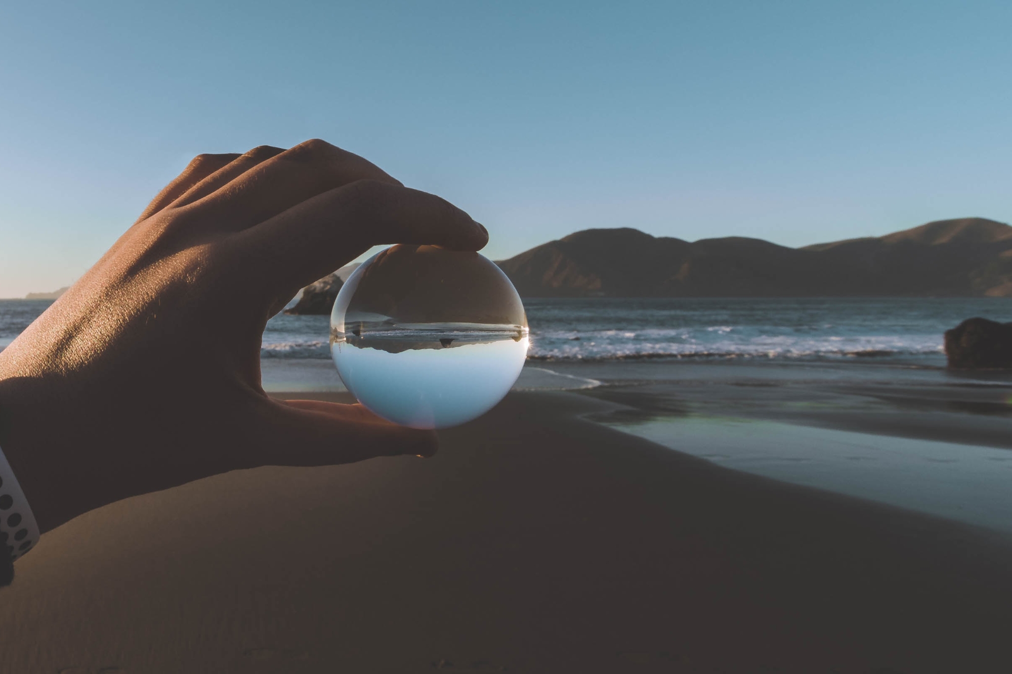 Hand Holding Glass Ball Sea